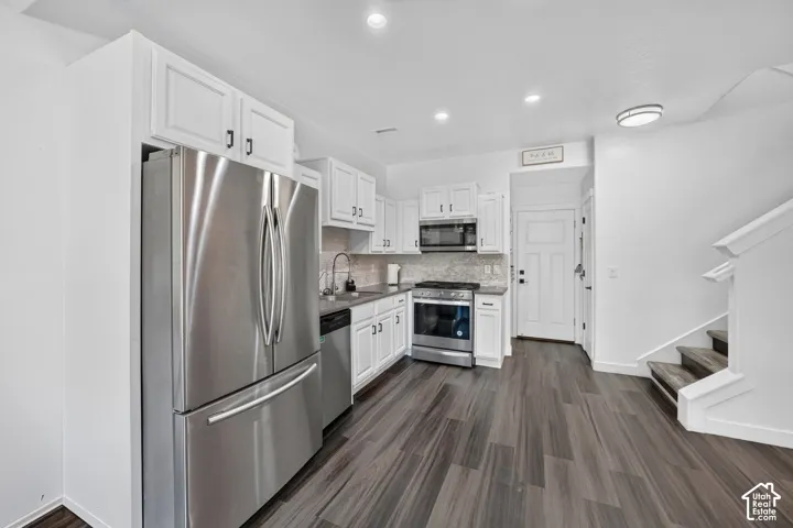 Kitchen featuring white shaker-style cabinetry, stone-finish countertops, stainless steel appliances, and wood-finish flooring