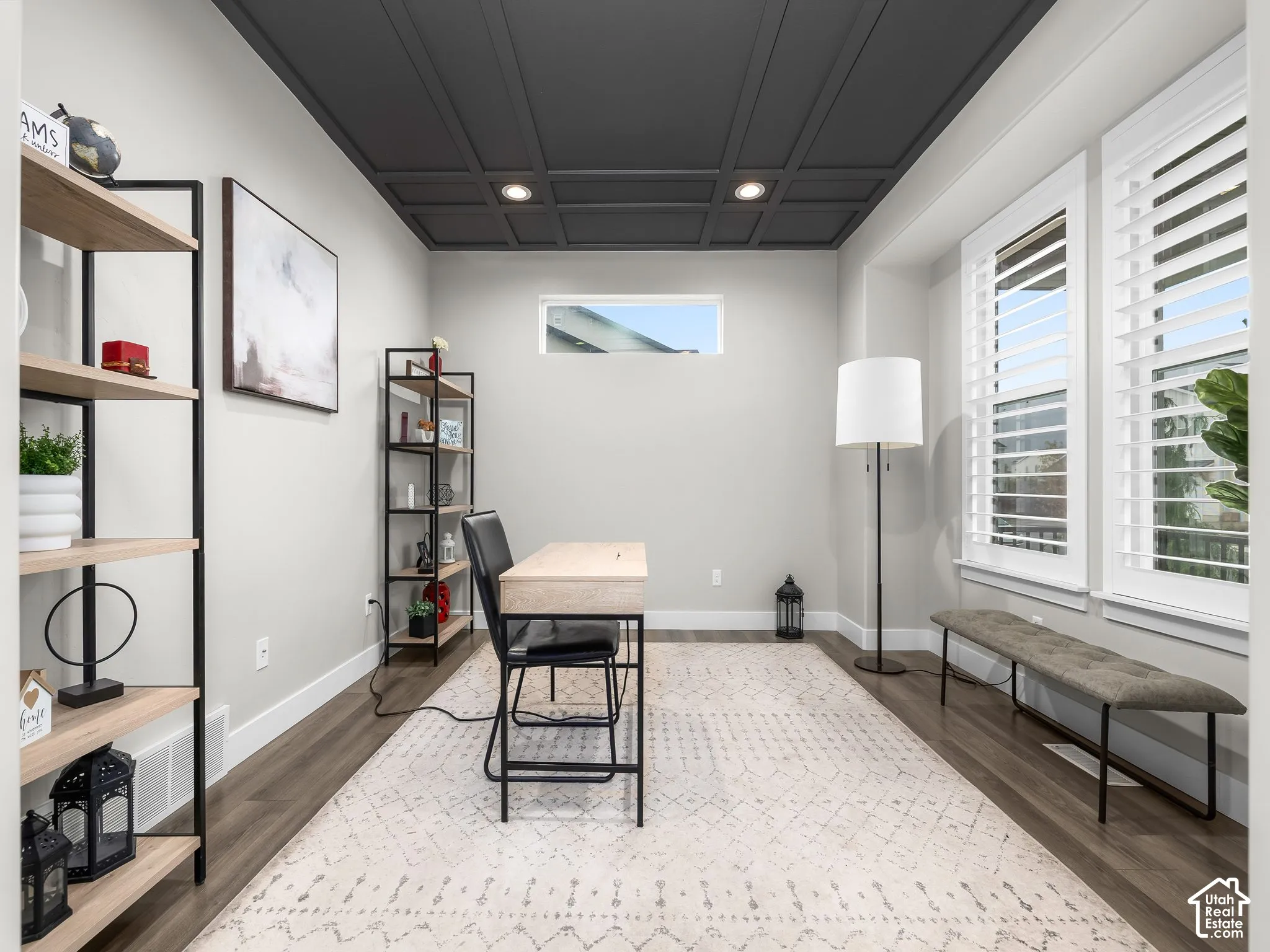Interior space featuring a dark-toned coffered ceiling, wood-finish flooring, recessed lighting, and windows fitted with plantation shutters