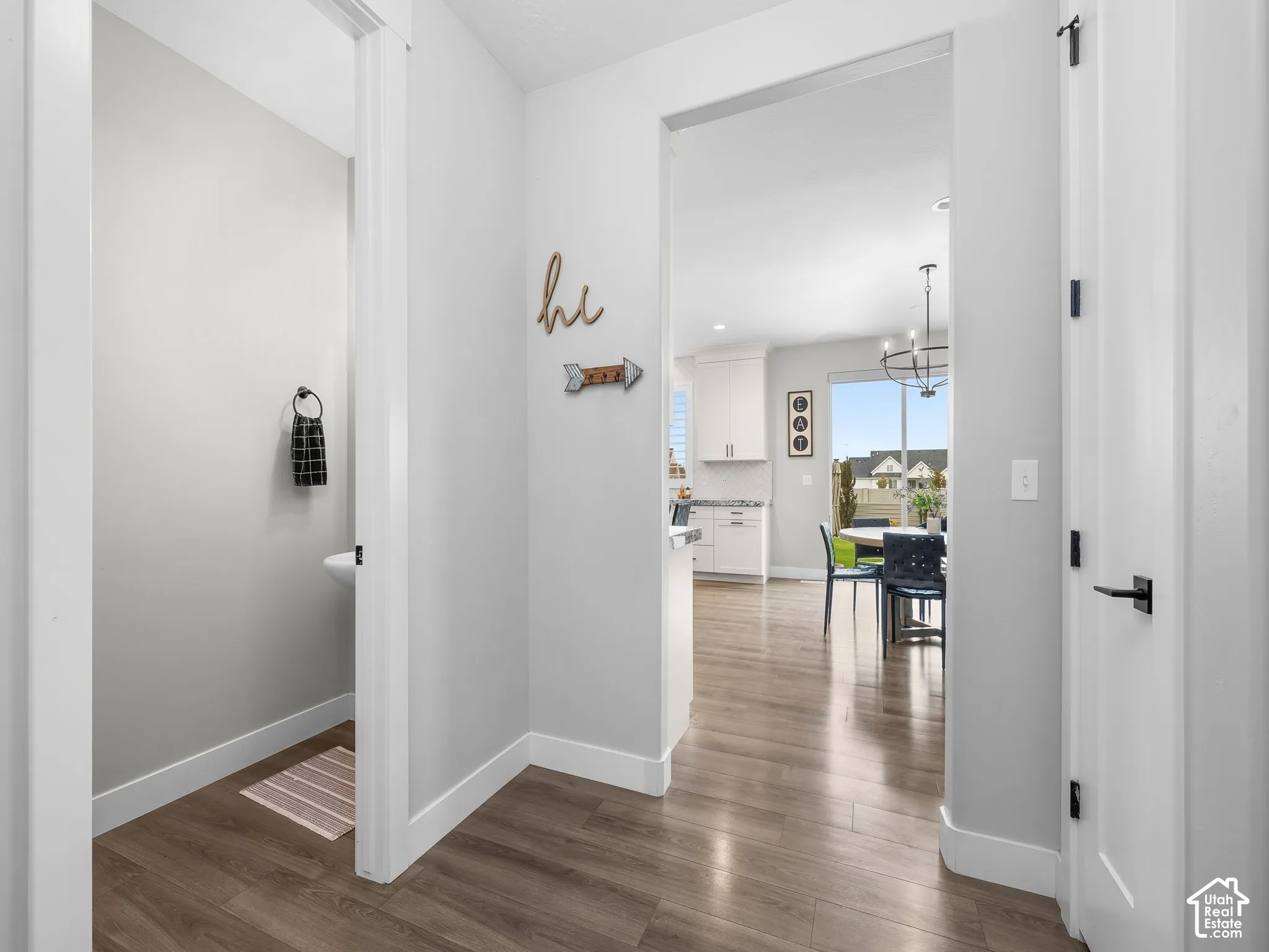 Neutral interior featuring wood-finish flooring, white paneled doors with matte black hardware, and crisp neutral wall paint