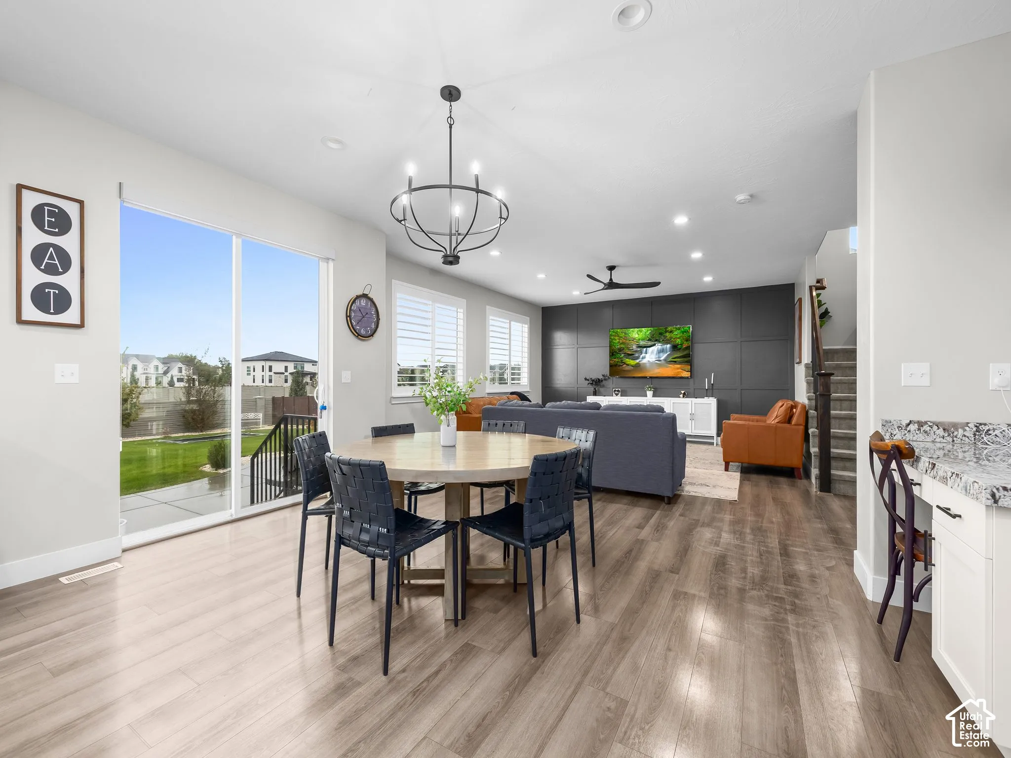 Open-concept area featuring wood-finish flooring, a dark paneled accent wall, sliding glass patio doors, a chandelier, and recessed lighting