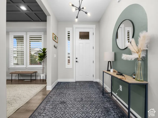 Entryway featuring wood-finish flooring, a modern multi-arm chandelier, and a decorative arched painted accent wall