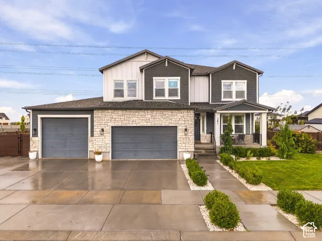 Multi-level exterior featuring stone veneer accents, vertical board-and-batten siding, shake-style siding, a three-car garage, and a covered front porch