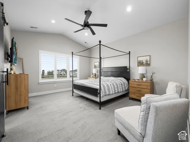 Vaulted ceilings, neutral carpeting, recessed lighting, matte black ceiling fan, and multi-pane window with installed shutters