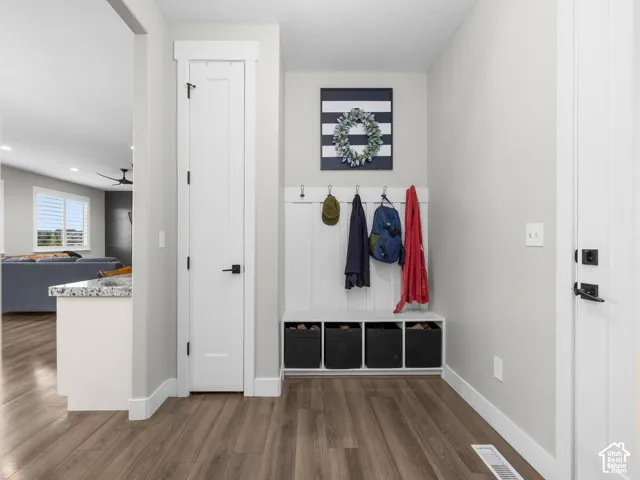 Entryway featuring wood-finish flooring, a built-in bench with open storage cubbies, white vertical plank wall paneling, and matte black hardware
