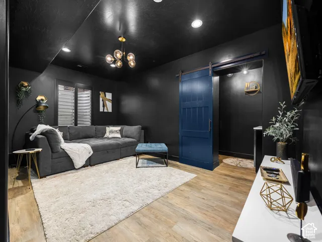 Wood-finish flooring, matte black ceiling, blue sliding barn door, multi-light modern chandelier, and recessed lighting