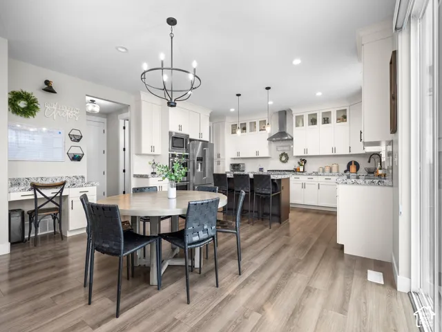 Kitchen featuring white cabinetry, wood-finish flooring, patterned stone countertops, a stainless steel wall oven, and a built-in workstation