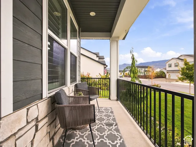 Covered front porch featuring dark horizontal lap siding, stone veneer base, recessed lighting, and black metal railing