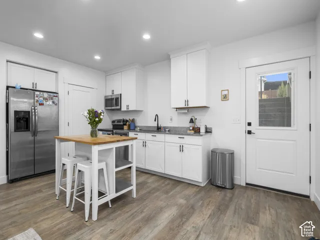 Kitchen featuring white cabinetry, stone countertops, matte black faucet, wood-finish flooring, and recessed lighting