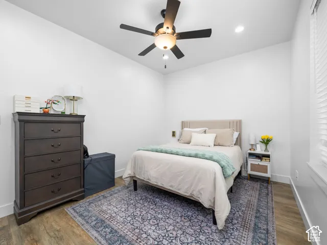 Room featuring wood-finish flooring, neutral wall paint, recessed lighting, and a multi-blade ceiling fan with an integrated light fixture