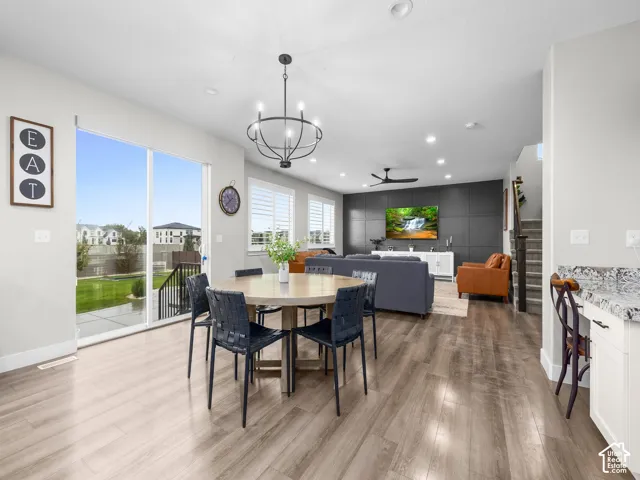 Open-concept area featuring wood-finish flooring, a dark paneled accent wall, sliding glass patio doors, a chandelier, and recessed lighting