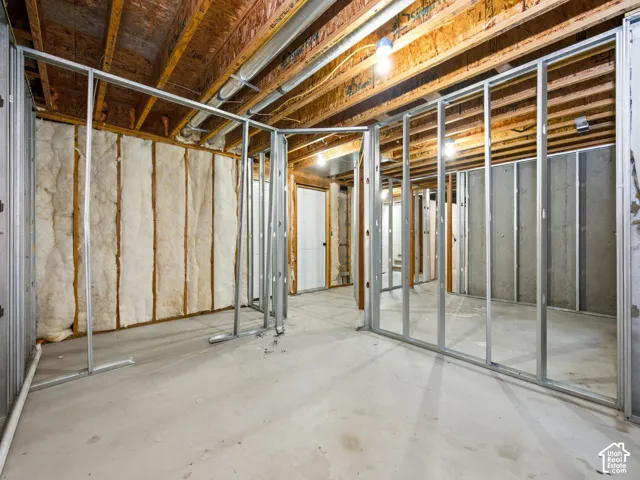 Unfinished area featuring exposed ceiling joists, concrete flooring, steel wall framing, and thermal batt insulation