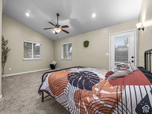 Vaulted ceiling featuring a central lighted ceiling fan, recessed lighting, wall-to-wall carpeting, and a glass-paneled exterior door