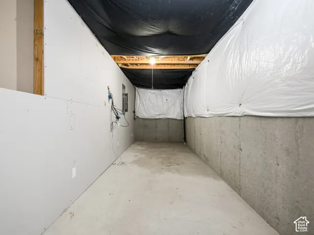 Unfinished lower level featuring concrete foundation walls, drywall panels, exposed ceiling joists, and an installed electrical panel