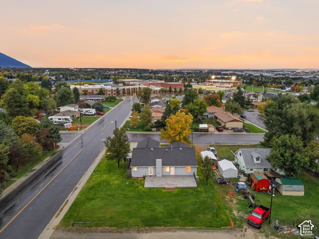 Aerial view featuring a single-story residence with a composite shingle roof, exterior chimney, and a concrete patio