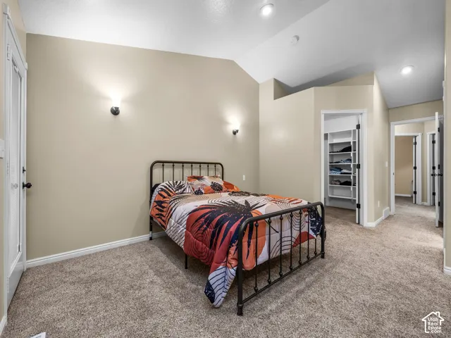 Vaulted ceiling featuring recessed lighting, wall-mounted accent sconces, wall-to-wall carpeting, and a walk-in closet with built-in shelving