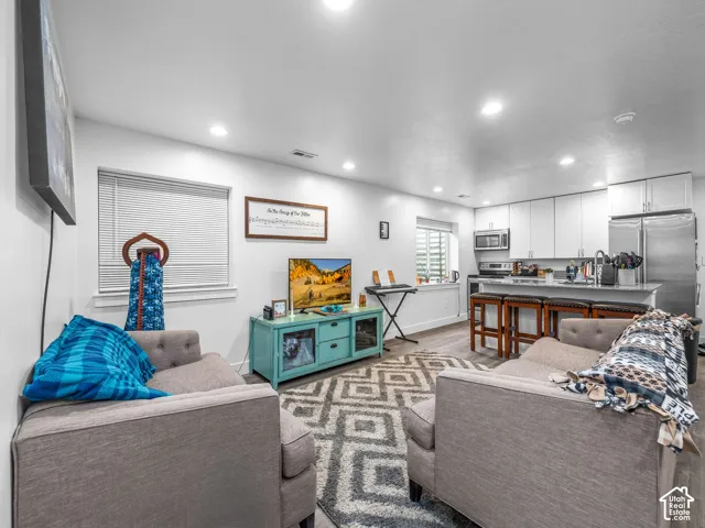 Open-concept interior featuring recessed lighting, wood-finish flooring, white shaker-style cabinetry, and a peninsula with quartz countertops