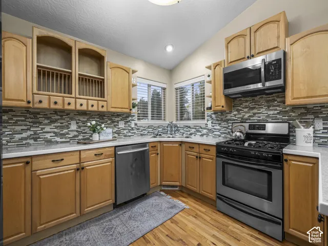 Kitchen featuring light-finish cabinetry, mosaic tile backsplash, stainless steel appliances, and solid surface countertops