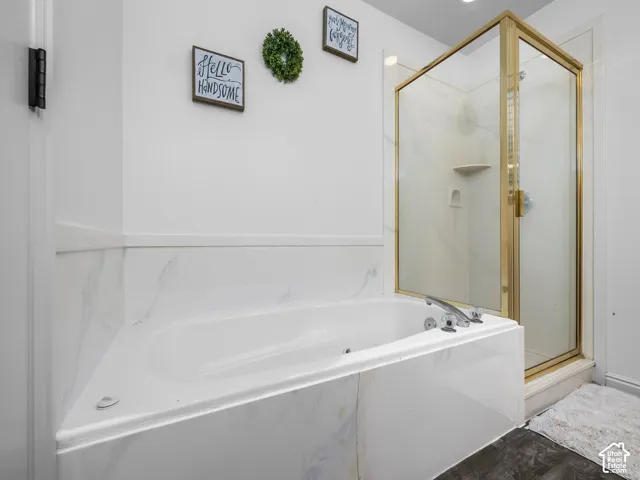 Soaking tub featuring stone-finish tile surround, separate shower enclosure with gold-tone frame, and integrated fixtures