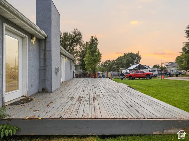 Expansive elevated wood deck with metal railing, stucco exterior siding, and exterior wall-mounted lighting