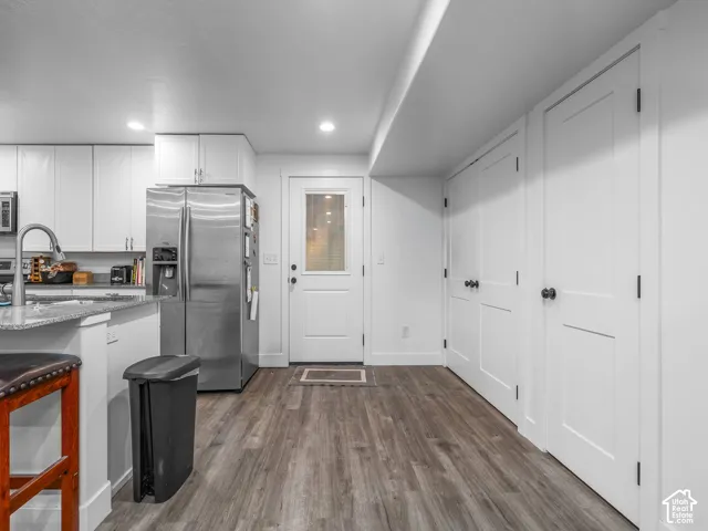 Kitchen featuring white cabinetry, stone countertops, wood-finish flooring, recessed lighting, and double-panel doors