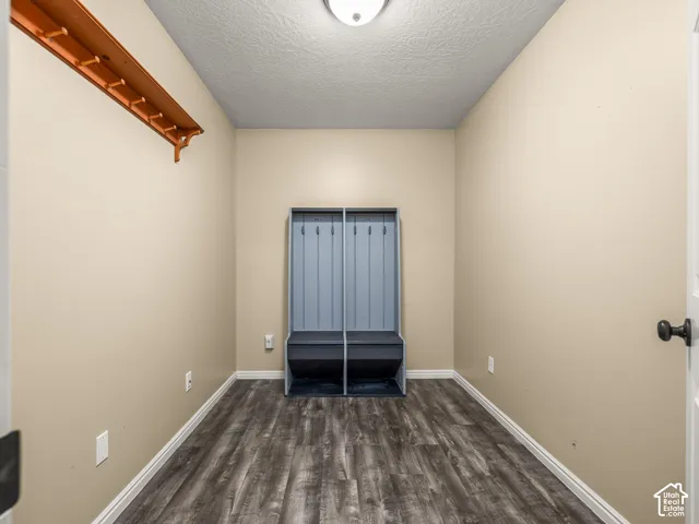 Built-in storage bench with paneling, wood-finish flooring, and wall-mounted wooden coat rack