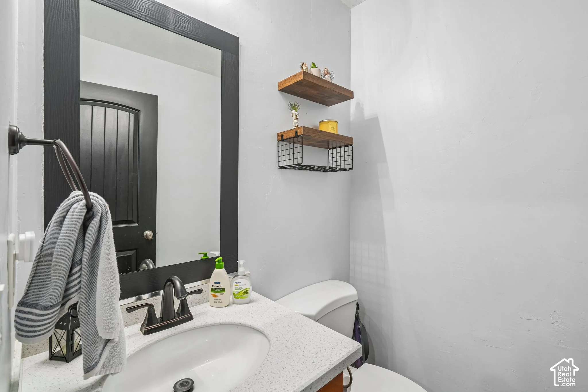 Bathroom featuring a vanity with a light-toned speckled countertop, an undermount oval sink, and a matte black faucet