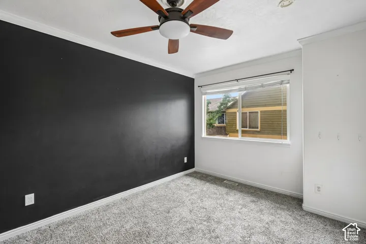 Interior room featuring a high-contrast black accent wall, ceiling fan with integrated lighting, wall-to-wall carpeting, and a window with a horizontal rod