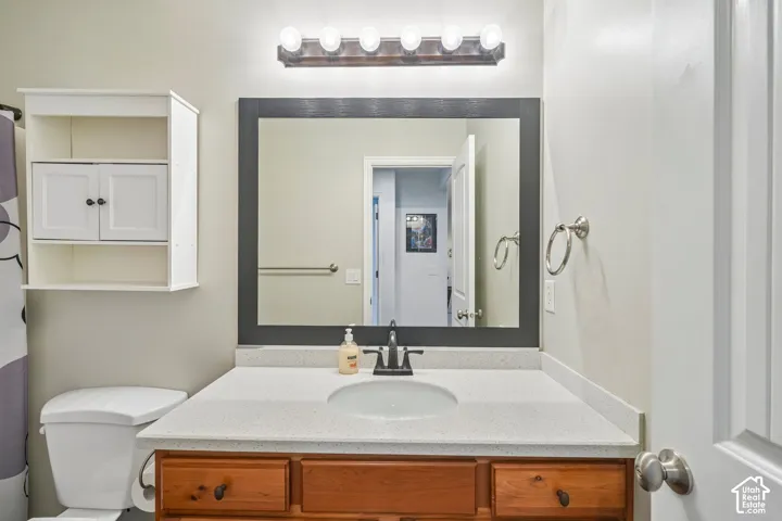 Bathroom vanity featuring a speckled composite countertop, undermount sink, dark-finish faucet, framed mirror, and wall-mounted storage cabinetry