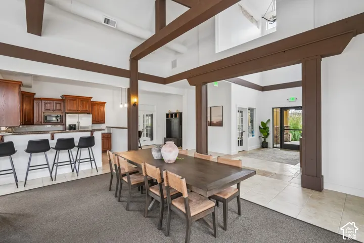 Vaulted ceilings featuring exposed structural beams, tile flooring, and custom cabinetry with an integrated breakfast bar