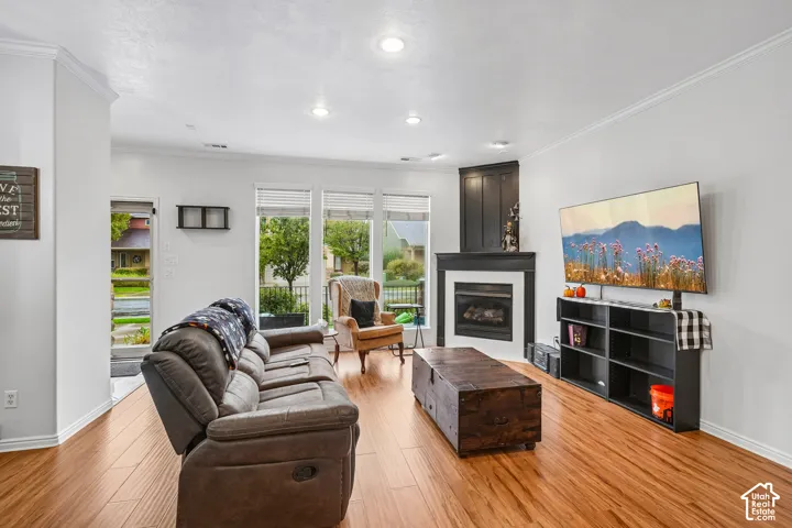 Living area featuring wood-finish flooring, recessed lighting, triple window configuration, and a corner fireplace with a custom wood surround