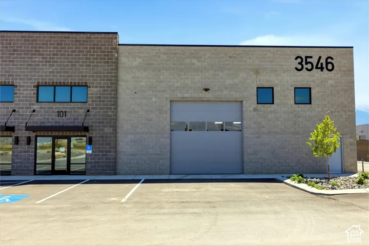 Contemporary commercial building featuring a gray block facade, a large roll-up door, and multiple windows