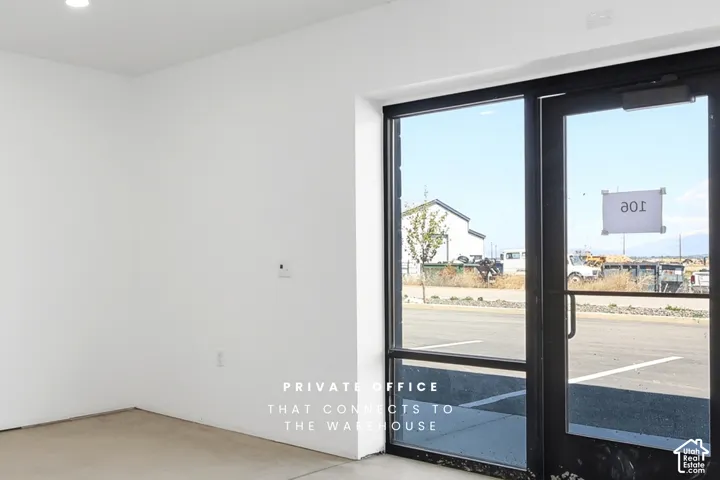 Recessed ceiling lighting, white painted walls, large storefront window, black-framed glass entry door, concrete flooring