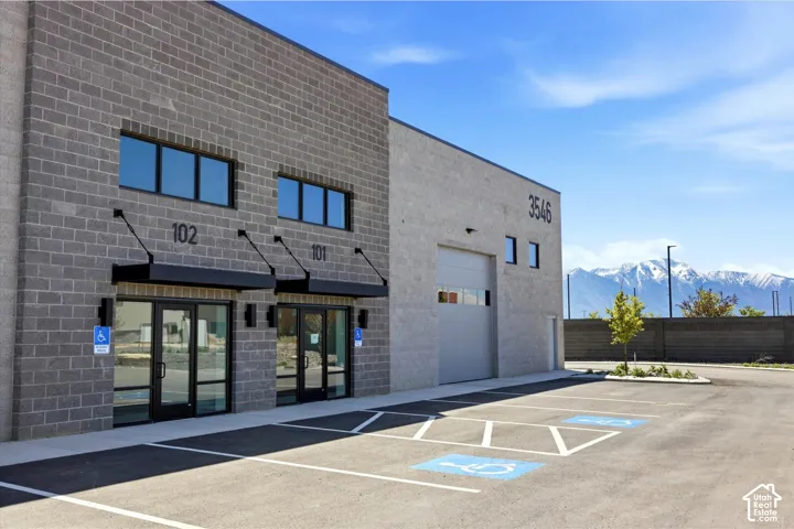 Commercial building featuring a block exterior, multiple entryways with awnings, a large roll-up door, and paved parking