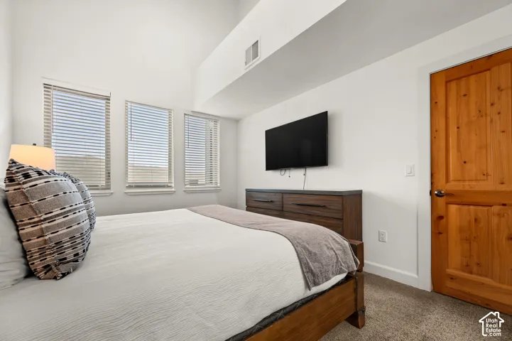 High vaulted ceilings featuring triple windows with horizontal blinds and a solid wood six-panel door