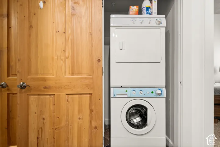 Stacked laundry unit featuring a front-loading washer and dryer, housed within a closet enclosure with natural wood-finish panel doors and brushed nickel hardware