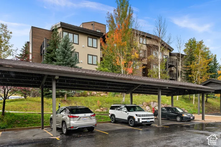 Multi-story exterior featuring wood and stucco siding, a covered carport, and tiered landscaping