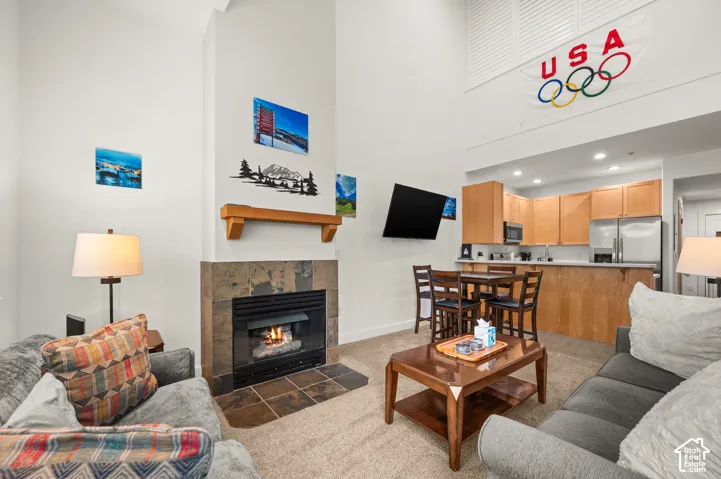 Vaulted ceilings, floor-to-ceiling stone-surround fireplace with a wooden mantel, and a kitchen featuring built-in cabinetry and a breakfast bar