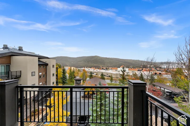 Elevated deck with black metal railing, mountain scenery, and mature deciduous trees