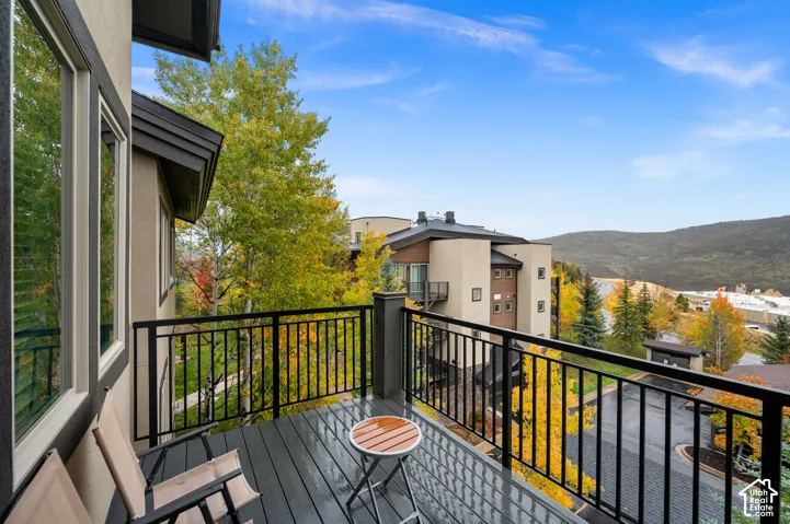 Elevated deck featuring composite flooring and a metal railing, complemented by expansive mountainous scenery and mature deciduous trees