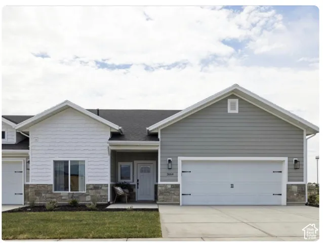 Exterior facade featuring mixed siding, stone veneer base, covered entryway, and attached multi-car garage