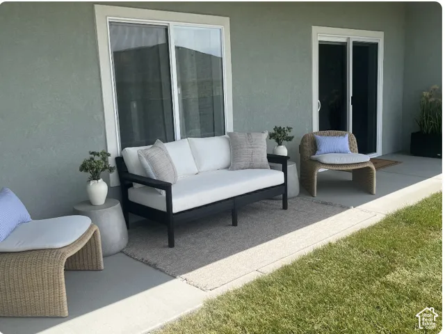 Covered concrete patio featuring dual sliding glass doors and manicured lawn space