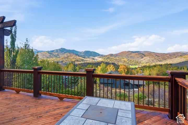 Expansive wood deck featuring a built-in pergola and railings with metal balusters, overlooking a mountainous landscape