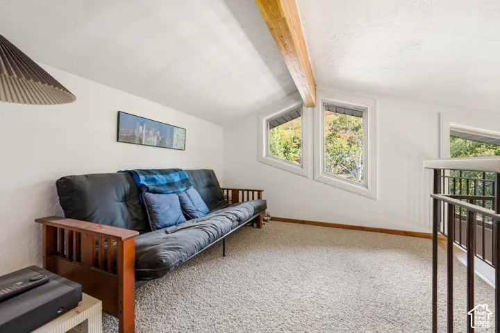 Vaulted ceiling featuring an exposed wood beam, geometric windows, and metal railing