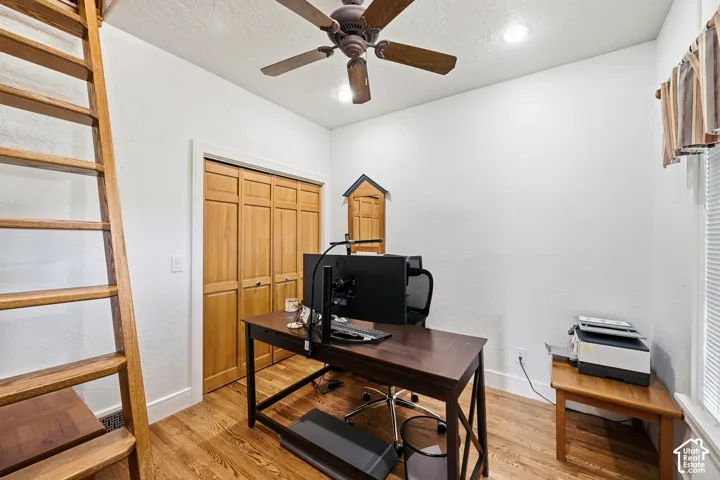 Wood-finish flooring, wood-toned bi-fold closet doors, ceiling fan, and built-in ladder