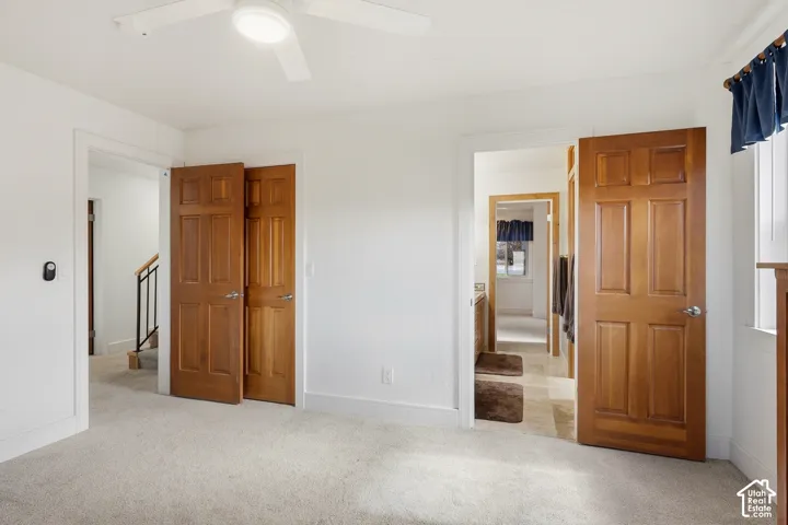 Neutral-toned carpeted flooring, solid wood six-panel doors, and a ceiling-mounted light fixture with integrated fan blades