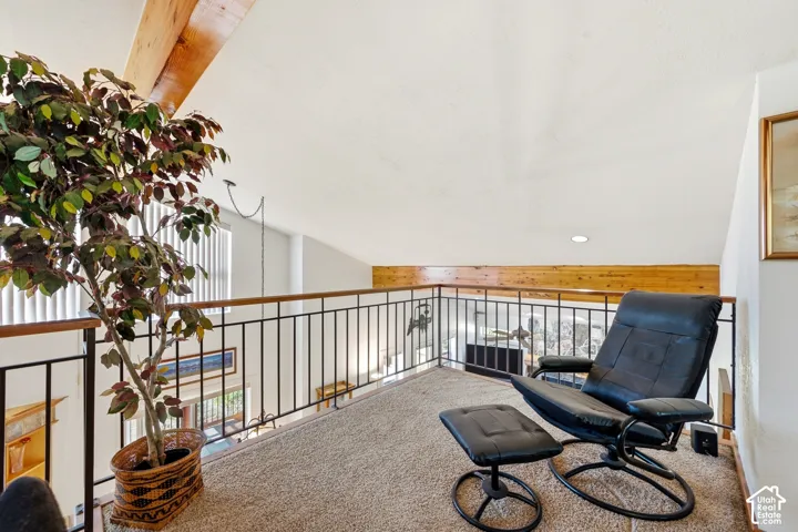 Vaulted ceiling with exposed wood beams, wood-trimmed railing, and metal balusters