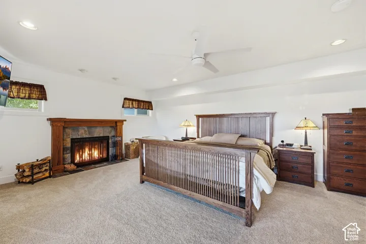 Fireplace featuring a stone surround and wood mantel, recessed lighting, and a ceiling fan