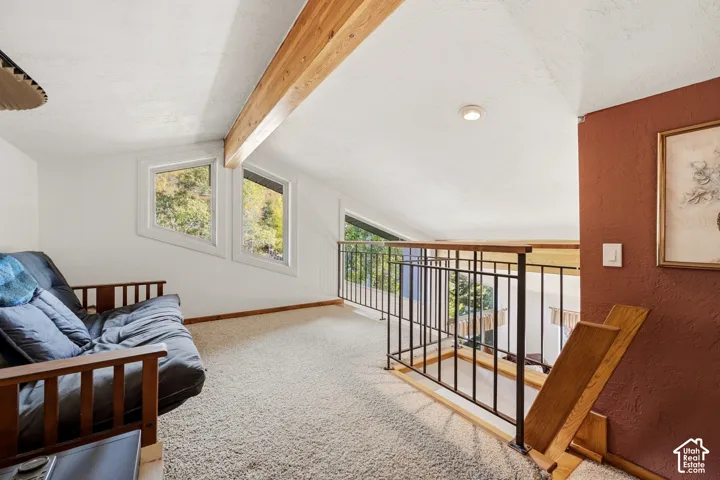 Vaulted ceiling with exposed wood beam, angular windows, and black metal railing