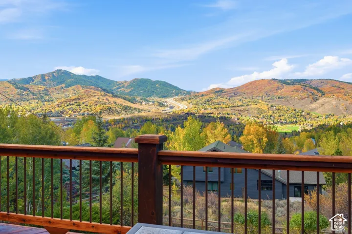 Elevated deck featuring a natural wood railing with vertical metal balusters and a wide, mountainous landscape backdrop