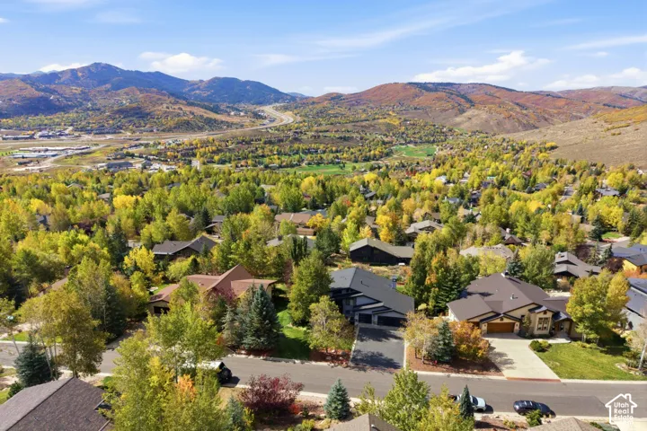 Aerial perspective featuring a residential community surrounded by mature deciduous trees and expansive mountainous terrain
